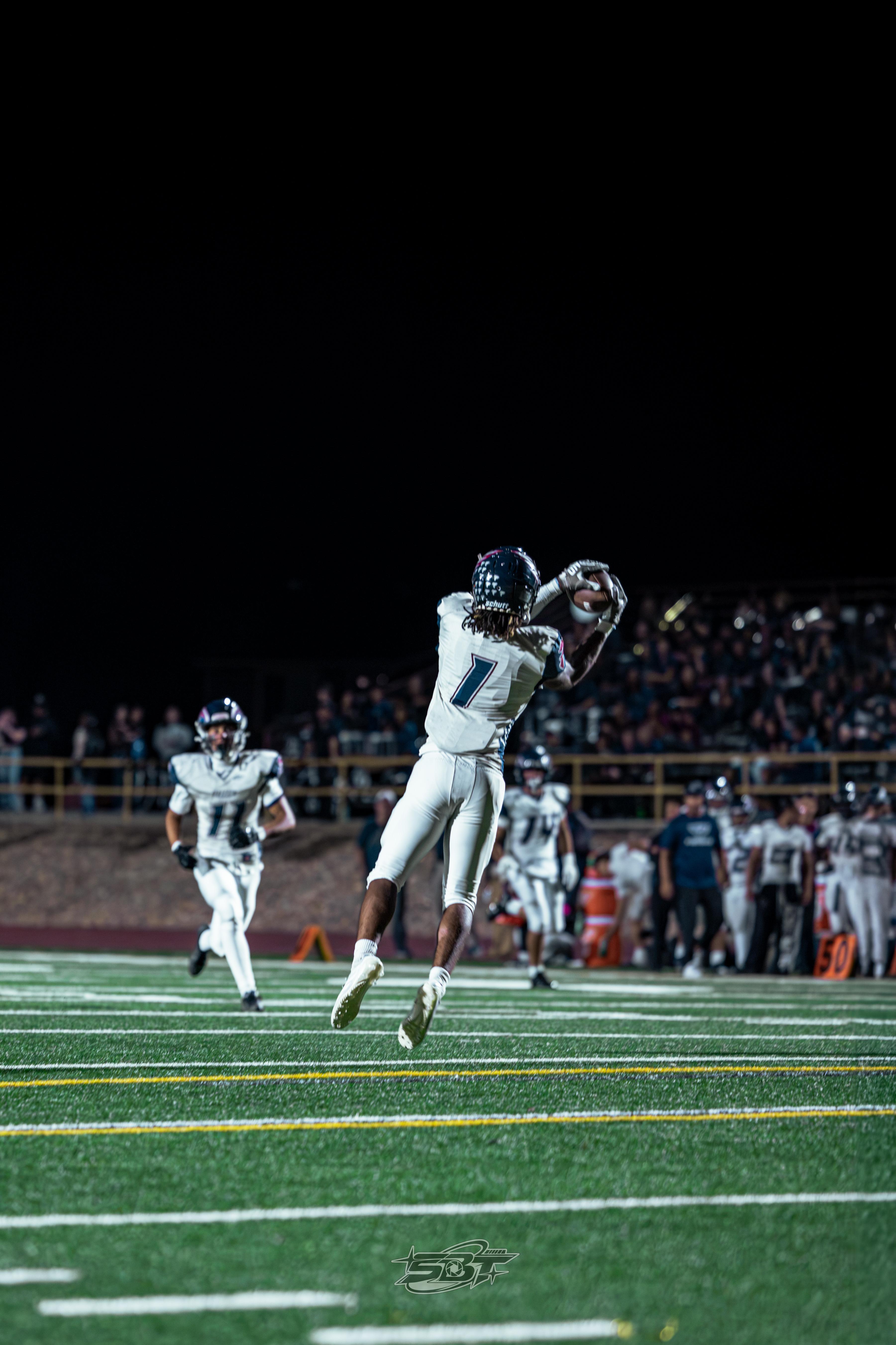 Freedom rushing the line against Liberty's punt formation, night game