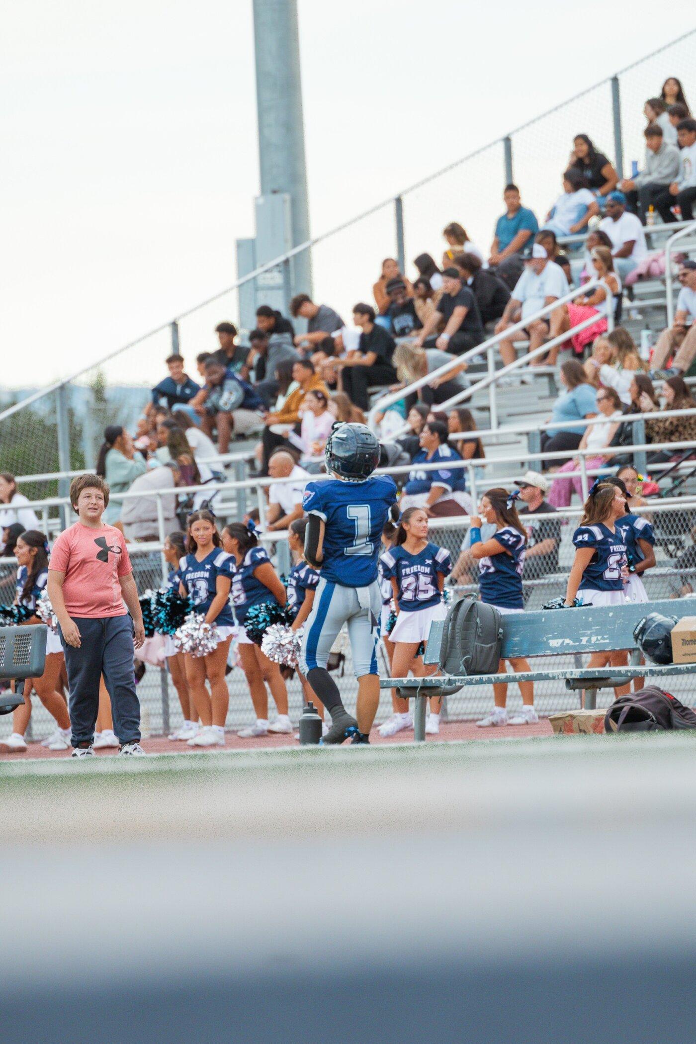 Freedom JV player on the sideline with cheerleaders in the background