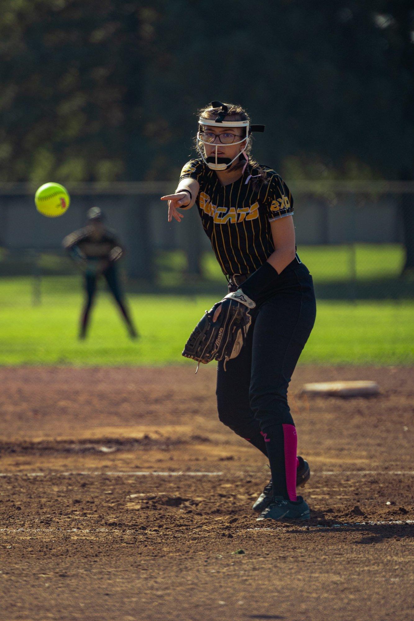Wildcats softball player throwing to first base